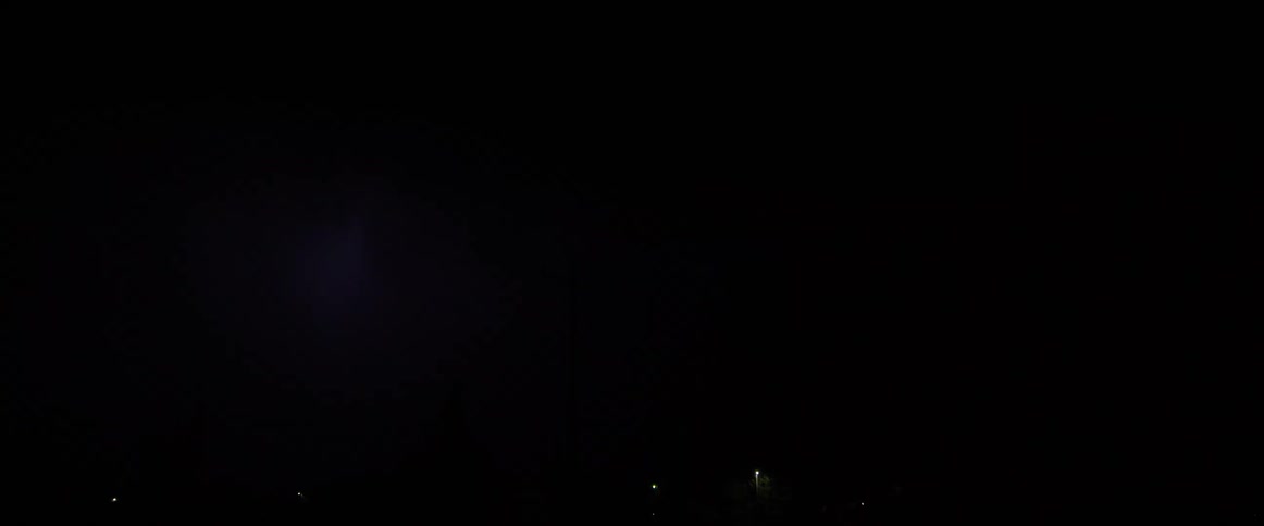 Lightning flashing on the clouds during a storm over a small town at night