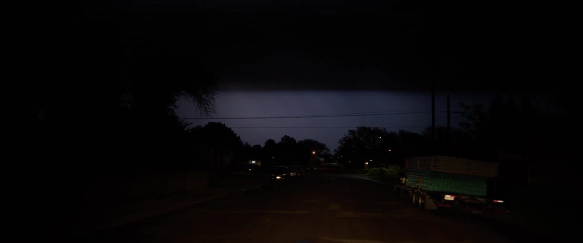 Lightning flashes in the sky as the vehicles travel