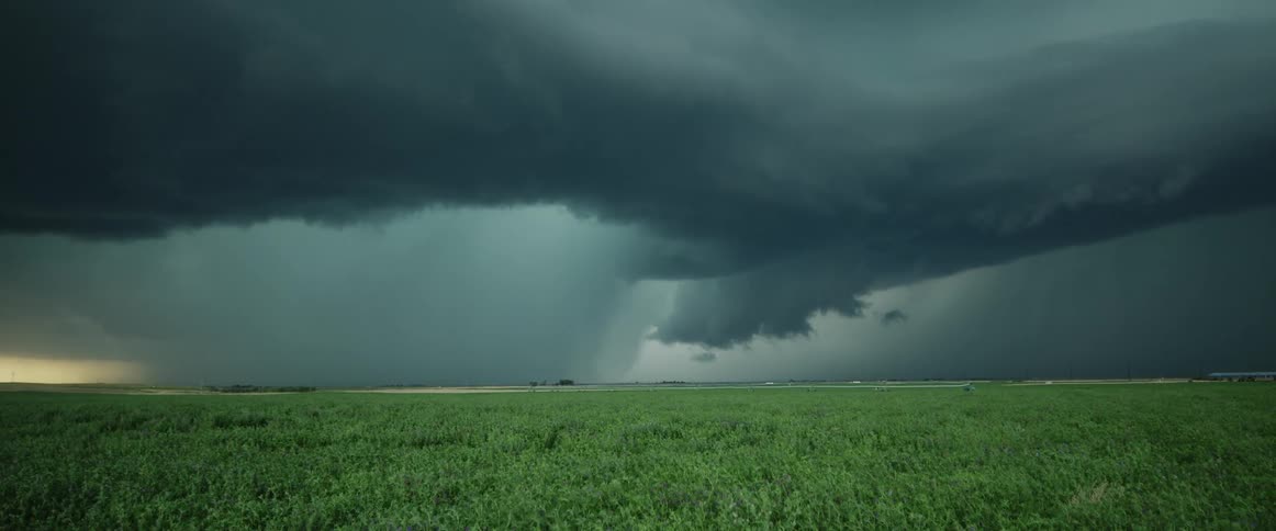 Rain pouring down dark storm thuderstorm clouds over the green fields