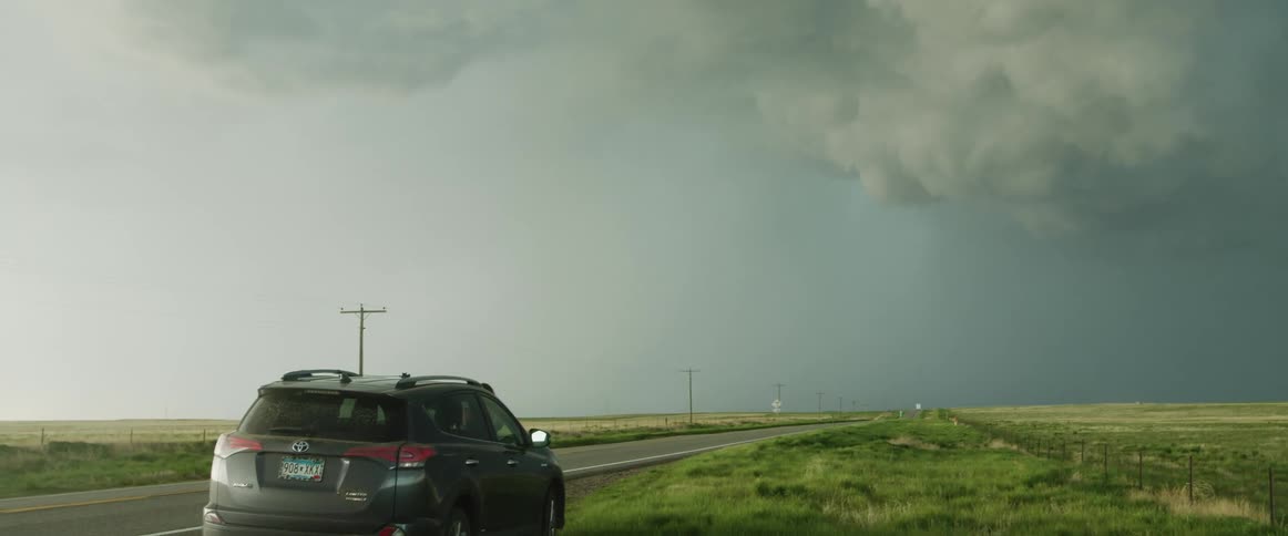 A vehicle is parked on the shoulder of the road during a storm
