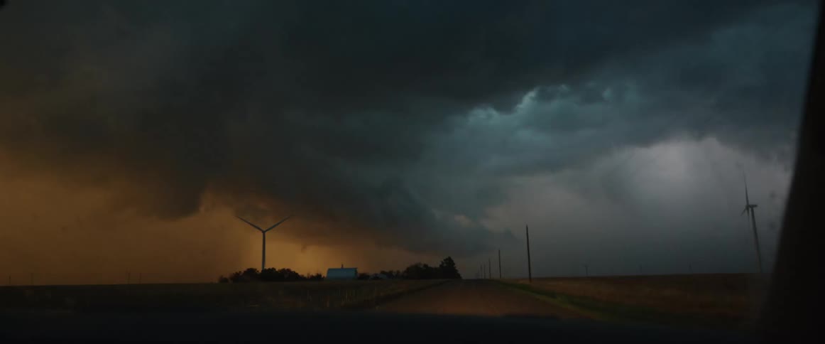 Dark storm clouds and lightning are in the sky as someone is driving into the storm