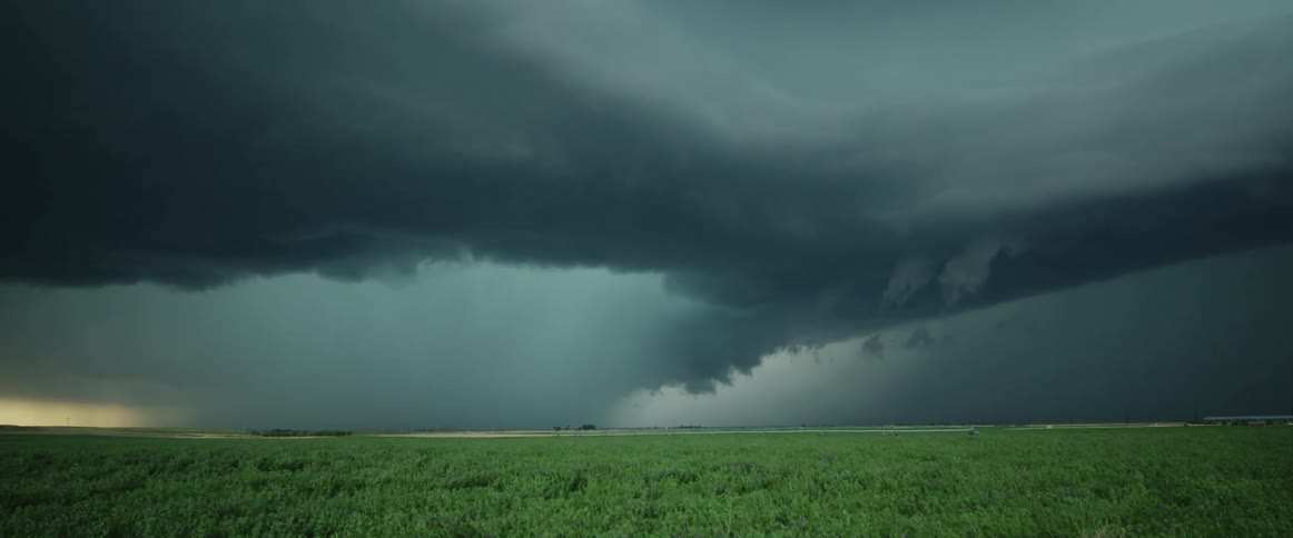 Lightning flashes in storm clouds over a grassland during the day