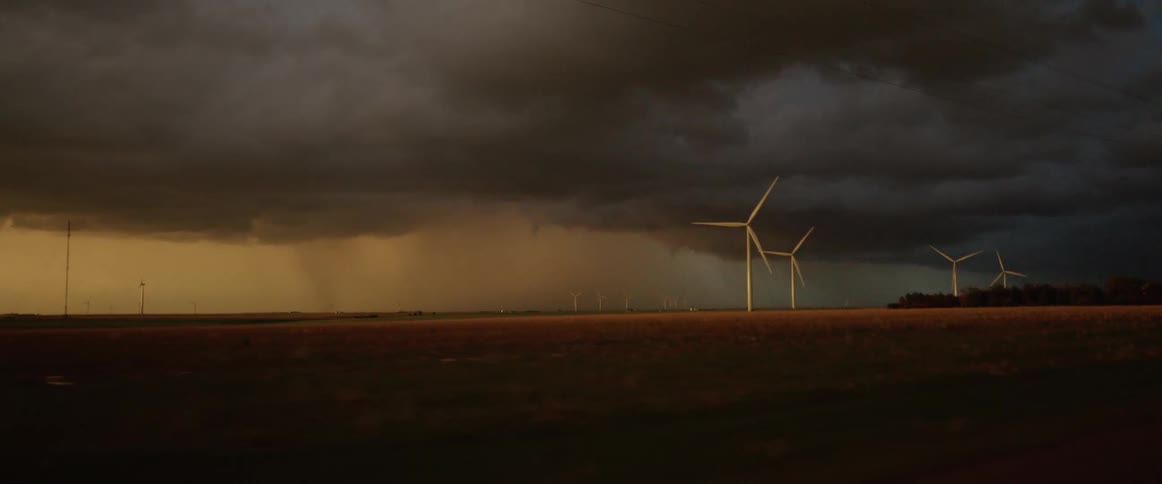 Lightning strikes among clouds as storm front hovers near wind farm