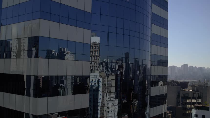 Skyscraper with glass windows reflecting the city skyline in the background