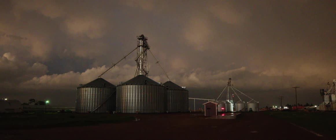 Storm clouds filled with lightning hover over a farm
