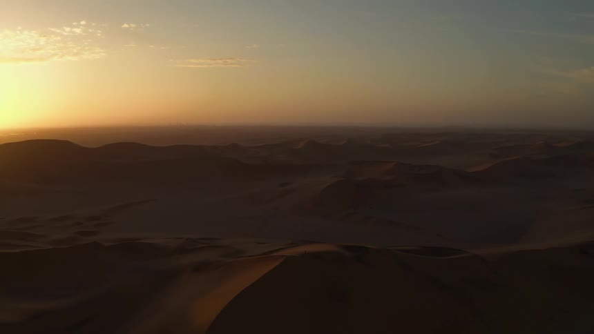 A desert landscape with dunes with the sky and clouds in the background