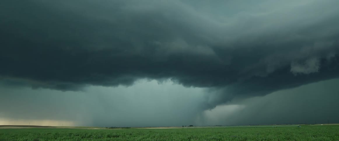 Lightning flashes in angry gray storm clouds over a wind blown field