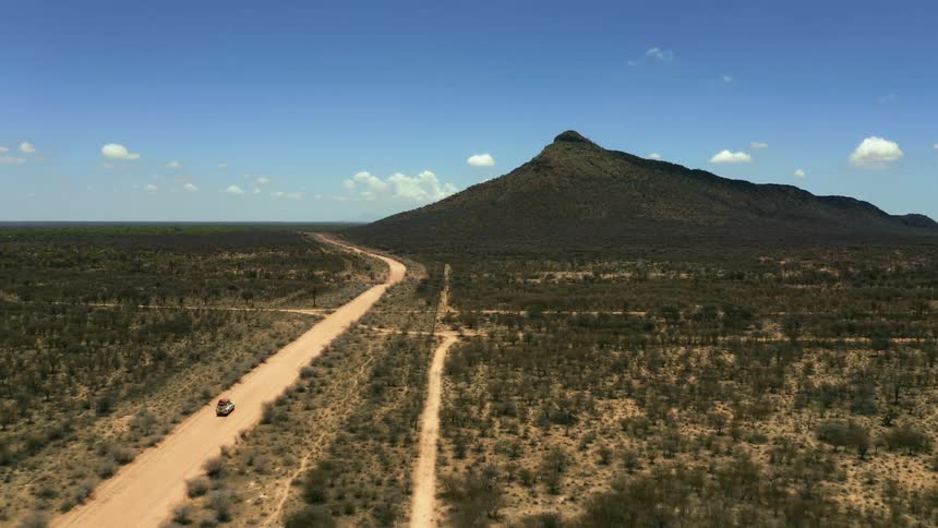 A sport utility vehicle drives down a dirt road toward a canyon