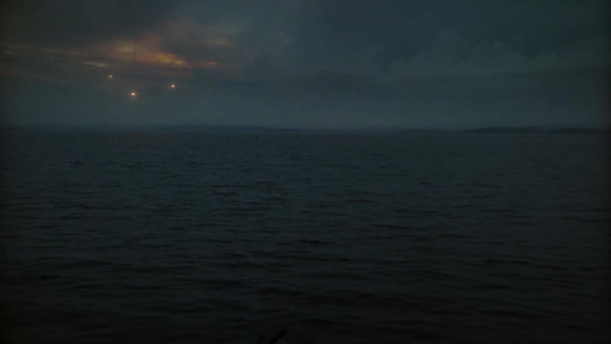 Three lights flicker as they slowly fall or fly towards the ocean surface