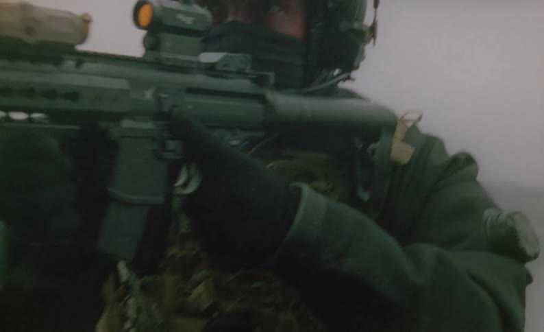 A soldier is wading in the water of a foggy lake while in full military gear pointing and aiming a highpowered rifle