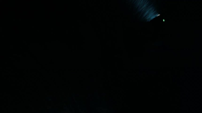 Man wearing headlight and walking through dark stops to look upward