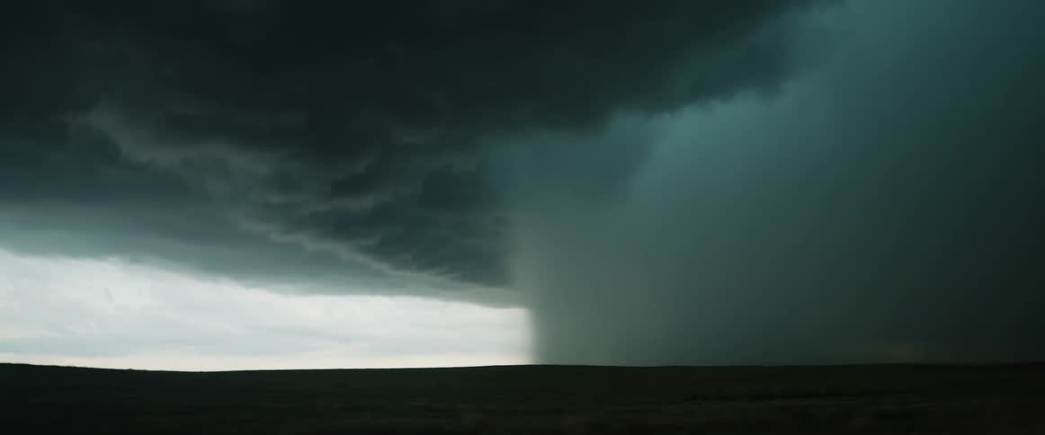 A very large tornado is on the ground in the distance