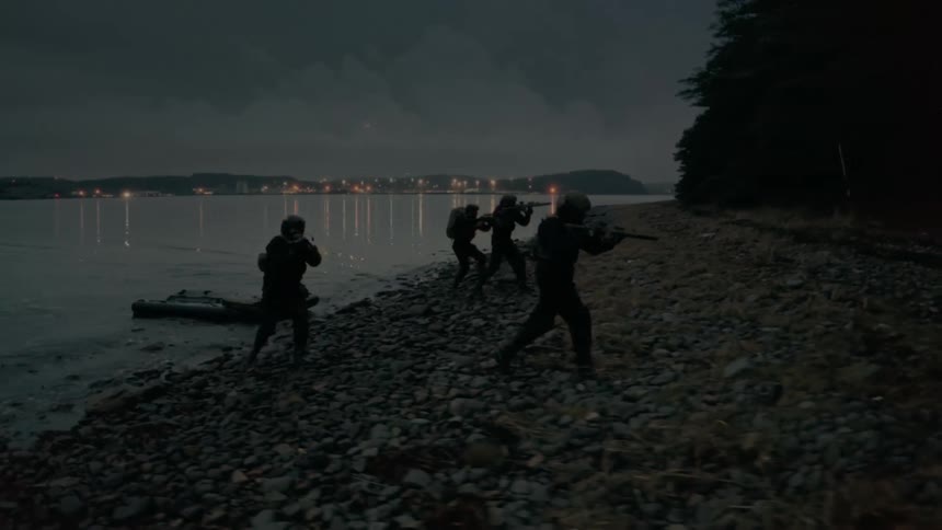 Soldiers walk out of a lake with rifles drawn as they make their way into the forest