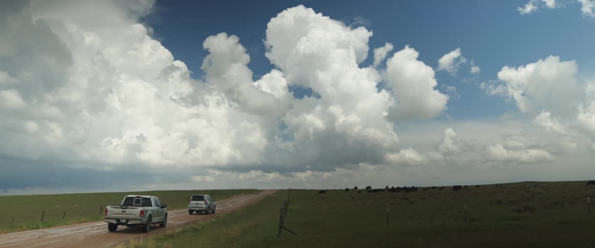 Two vehicles are parked on a dirt road in the desolate countryside