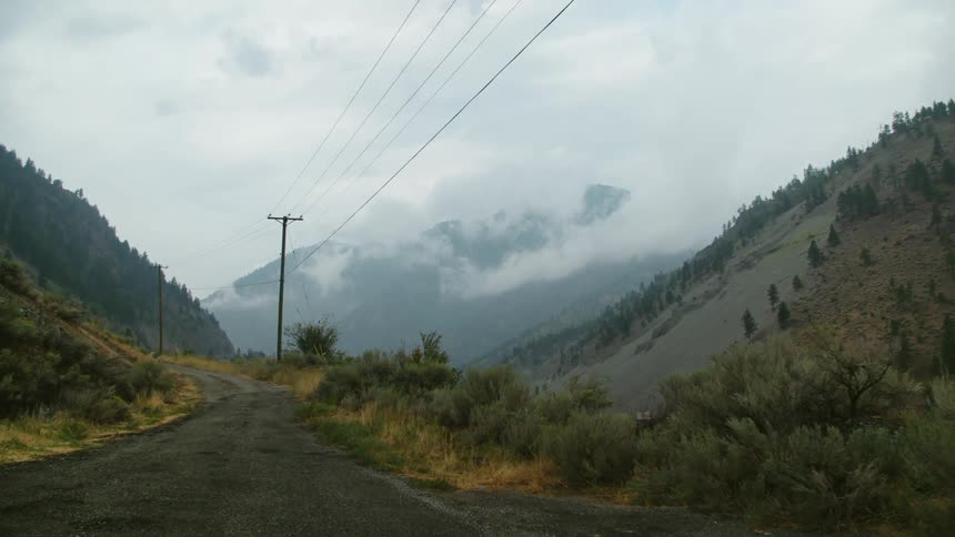 A narrow road runs between two tall hills in the countryside