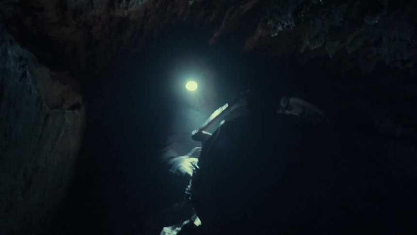 A man is moving through the dark cave