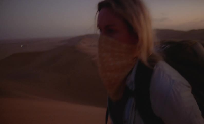 A woman hiking up a sand dune