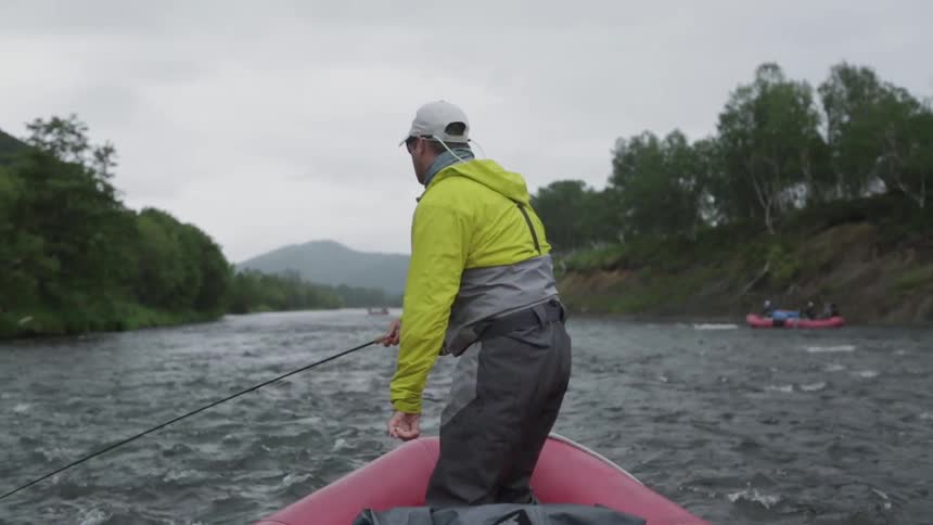 A man is fishing off the edge of a raft