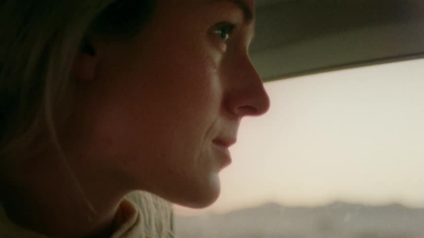 A woman rides as in a car traveling through the countryside during the day