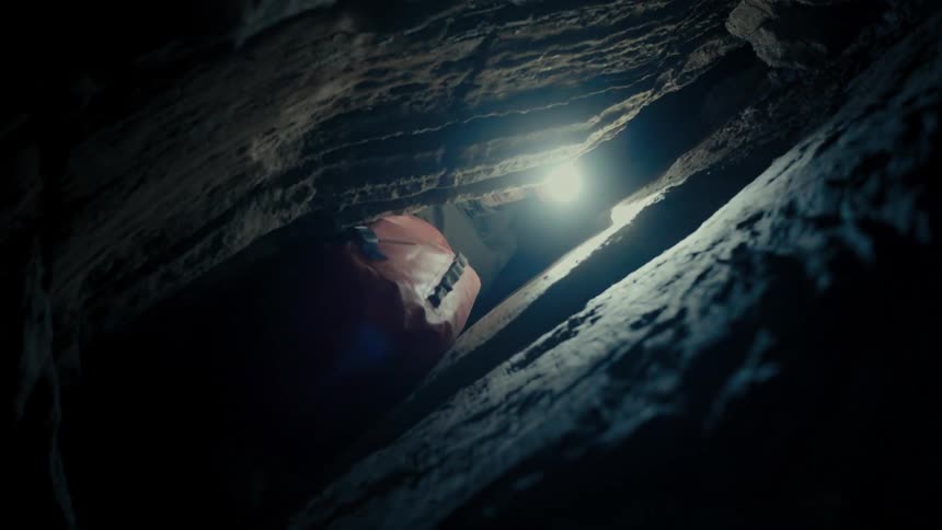 A man with gloves a helmet and a flashlight in a cave