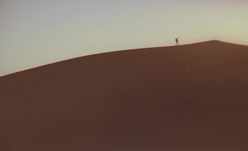 A person is hiking up the ridge of a mountain towards the peak
