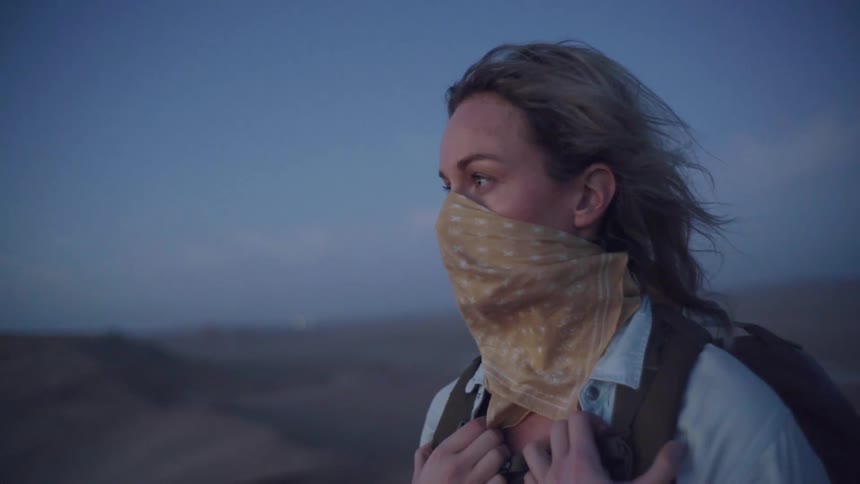 A woman walking at the top of a dune in the desert