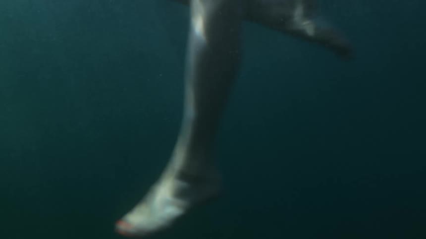 A person kicks their legs while swimming in deep water