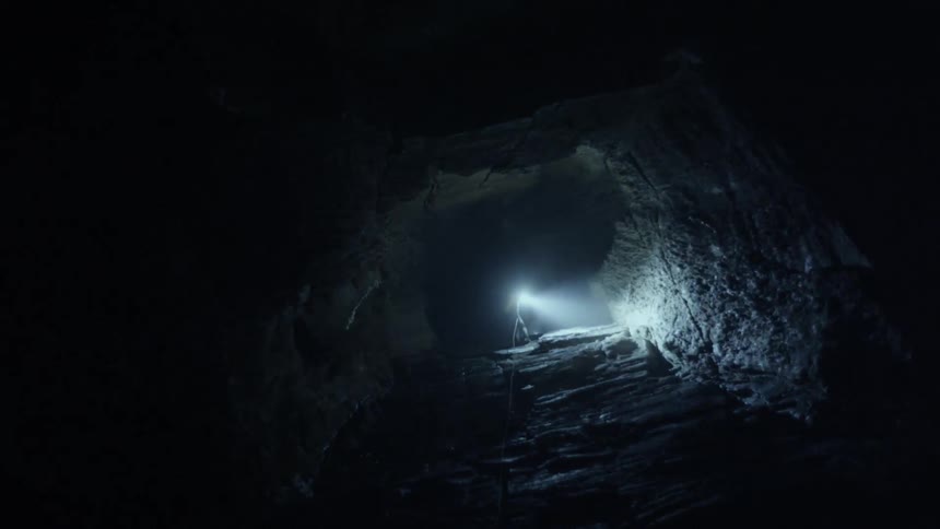 A person walking around in a cave with a headlamp