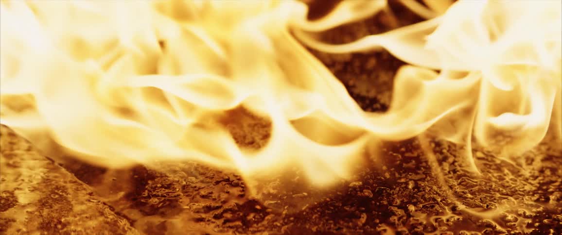 Flames rise from oil being cooked on a cast iron pan