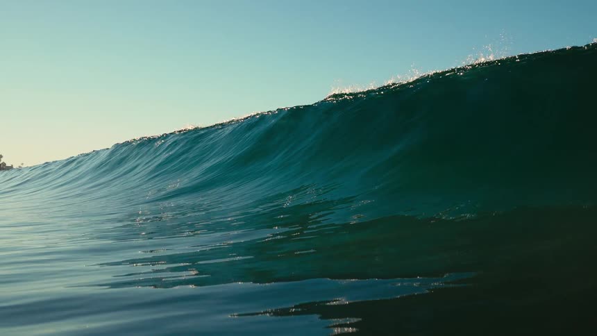 Close up of a small ocean wave crashing over the camera at morning