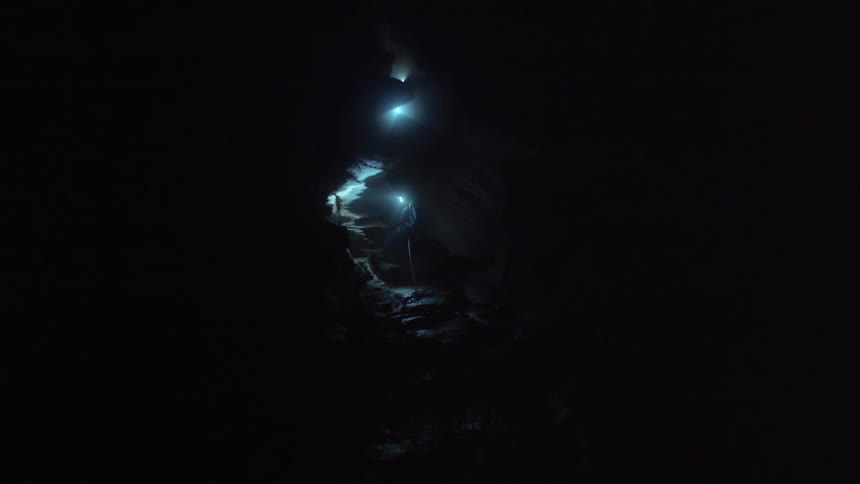 A person with a flashlight and a rope in a dark cave