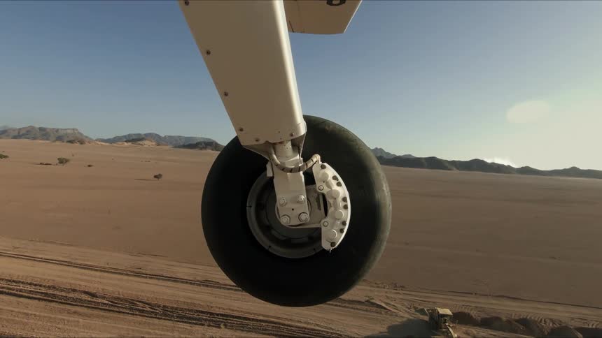 An airplane wheel rolls across the ground and lifts into the air
