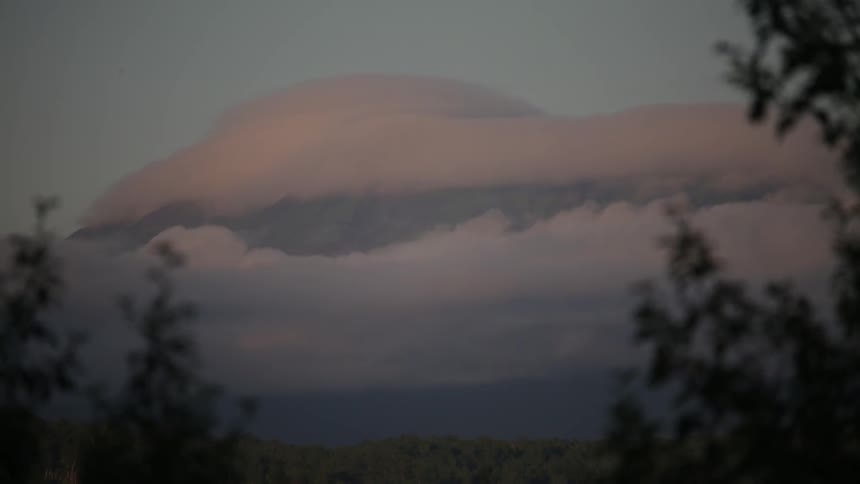 A mountain surrounded by clouds at dusk