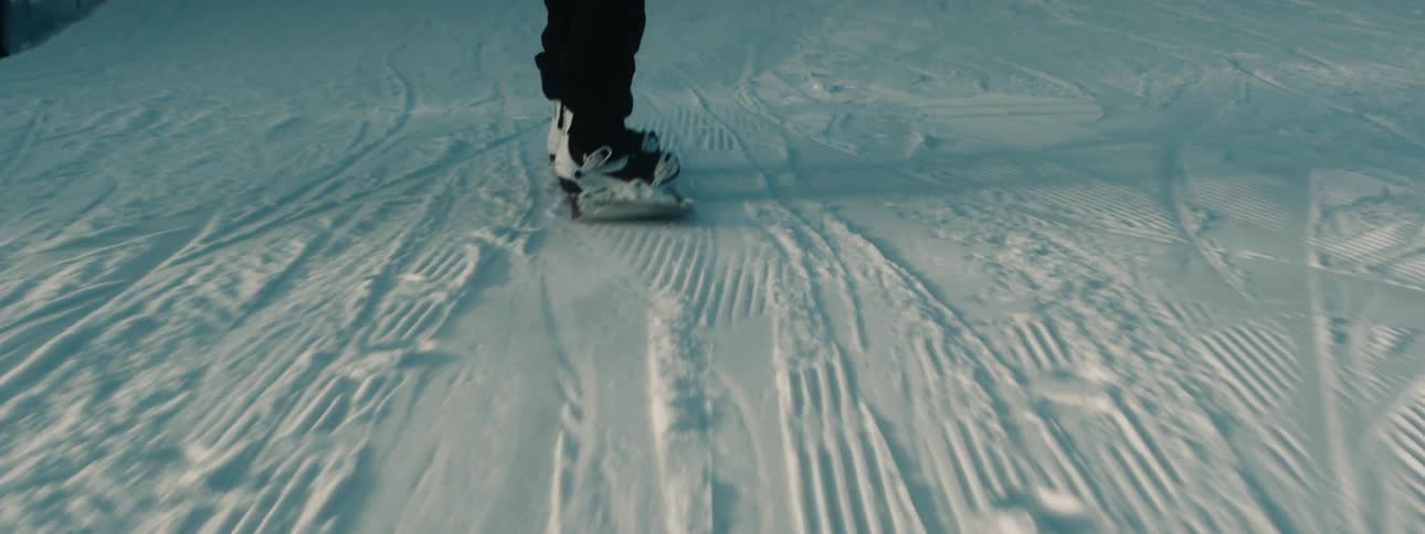 A snowboard rider coasts down a snow covered hill