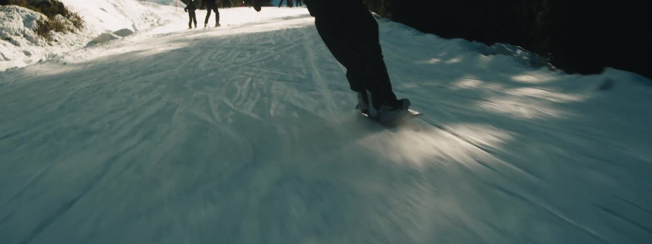A snowboarder jumps and does a spin while descending a snowy slope during the day