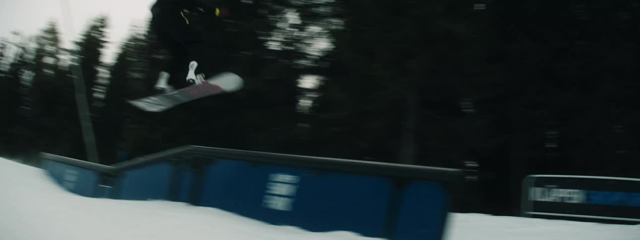 A snowboarder twirls mid air after coming off a snow ramp on a slope