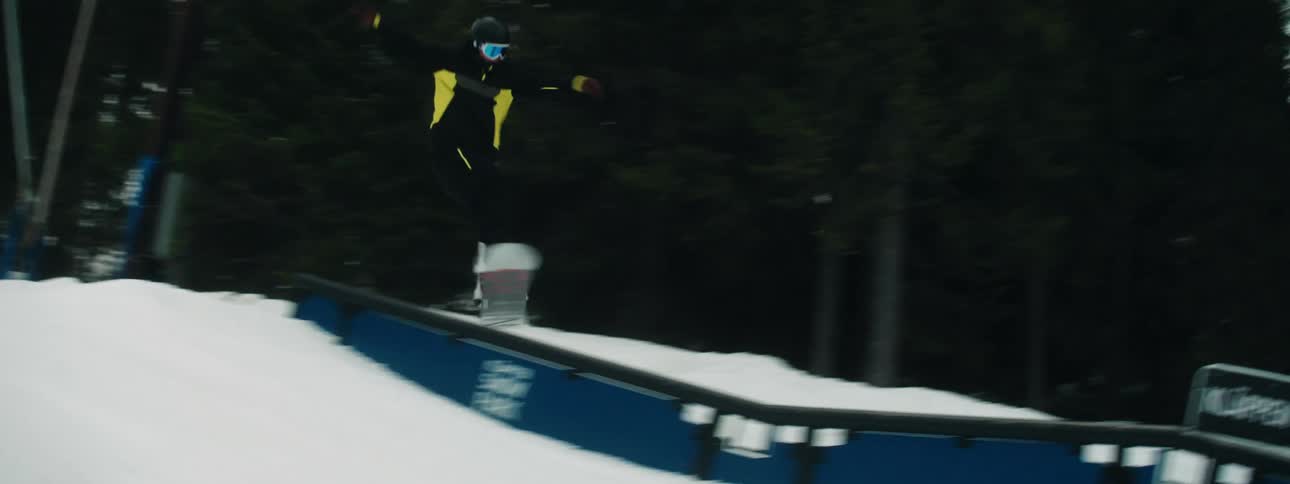 Snowboarder rides board down course toward buildings