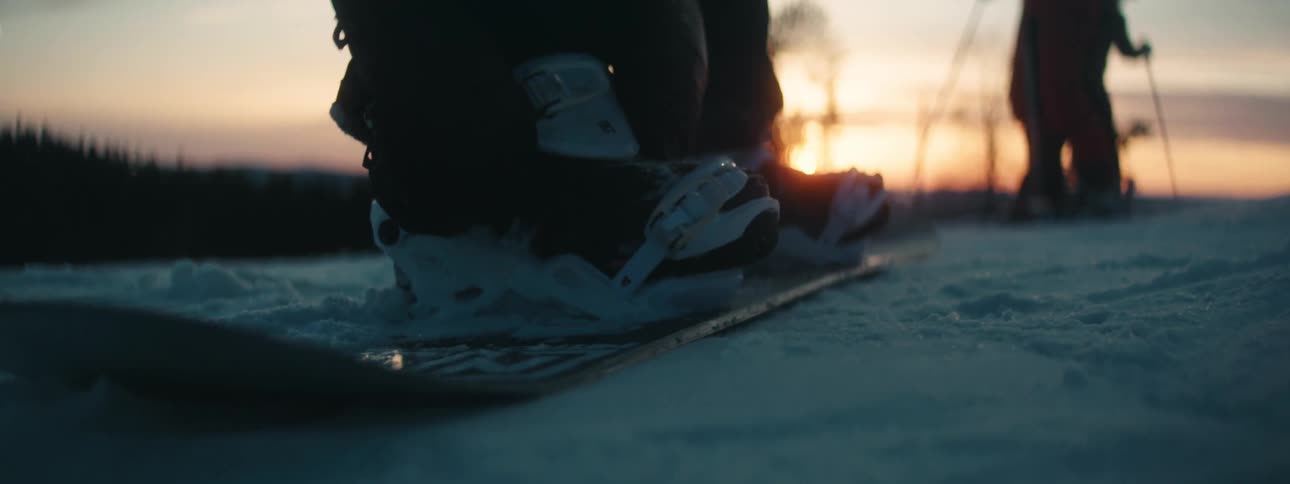 A person is attaching their snowboard latches