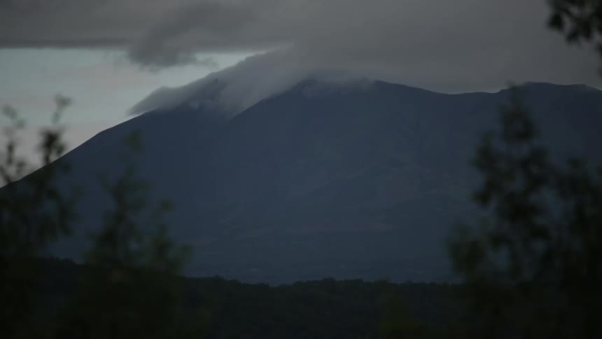 A cloud hangs over the tip of a mountain