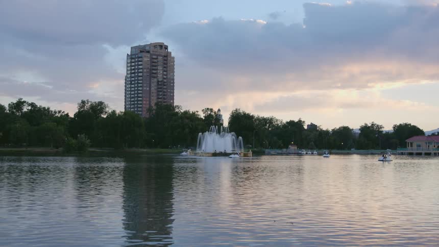 People relax in small boats on a lake near downtown