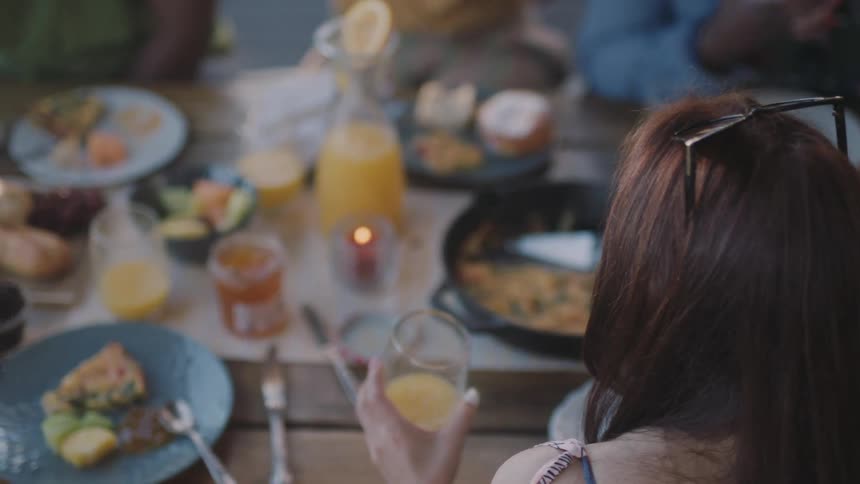 A man and woman are drinking and talking at a table with other people