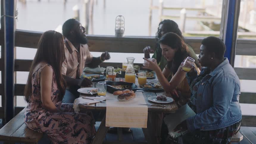 A group of friends are having breakfast at a restaurant with large windows
