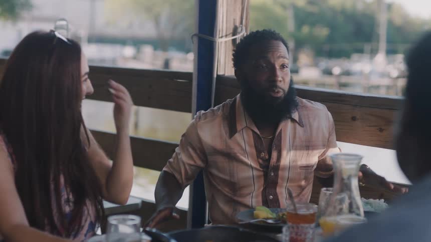 Friends are having a meal and casual talk at an outdoor restaurant near a citys waterway