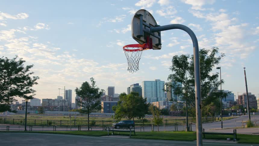 A basketball hoop on an outdoor court in a metropolis during the day