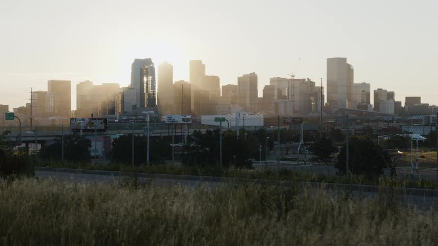 Tall buildings and skyscrapers loom over a freeway in a metropolis during the day