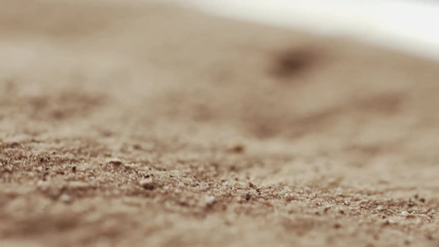 Close up of shifting waves of moving brown grains of sand