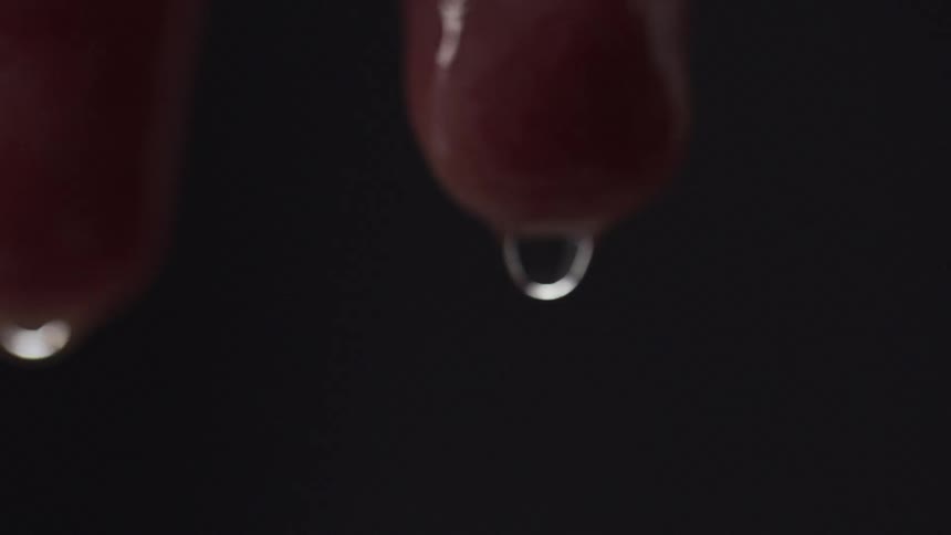Water drops fall from fingertips against dark gray background