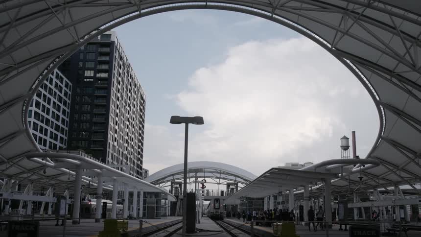 A large group of people linger and walk around a train station near downtown