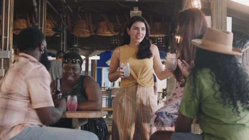 A group of people have drinks together and talk at a bar