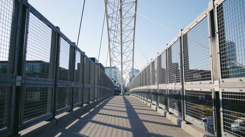 Pedestrian bridge with mesh sides spans highway in city